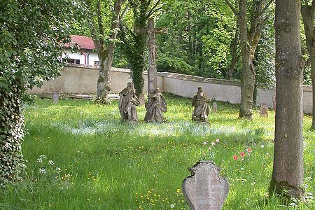 im Vordergrund ein Grabstein, im Hintergrund die barocke Kreuzigungsgruppe