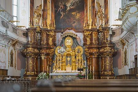 Barocker Kirchenaltar mit reich verzierten goldenen Elementen und Gemälde im Hintergrund.