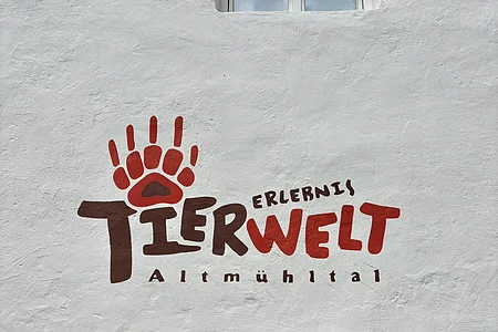 das Logo der Erlebnistierwelt Altmühltal ist auf einer Hauswand zu sehen. Das Logo hat die Farben Rot und Braun