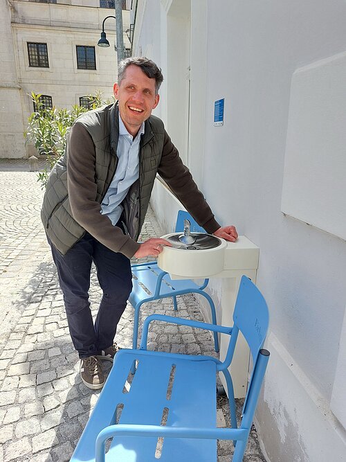 Oberbürgermeister Josef Grienberger testet als Erster den neuen Trinkwasserbrunnen am Domplatz.