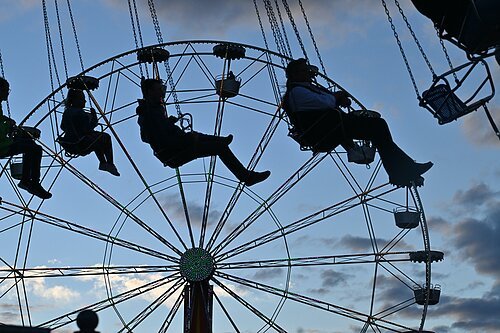Kettenkarussell und Riesenrad im Hintergrund in der Dämmerung